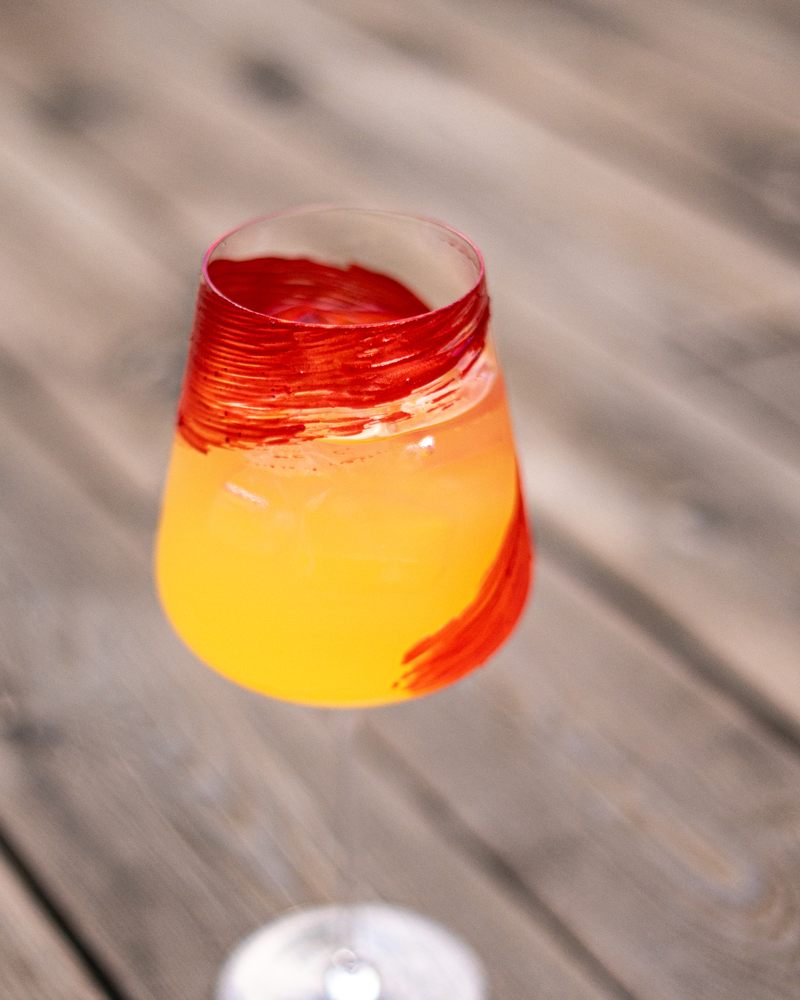Oransje cocktail i et glass med et rødt strøk av PAINTZ på innsiden